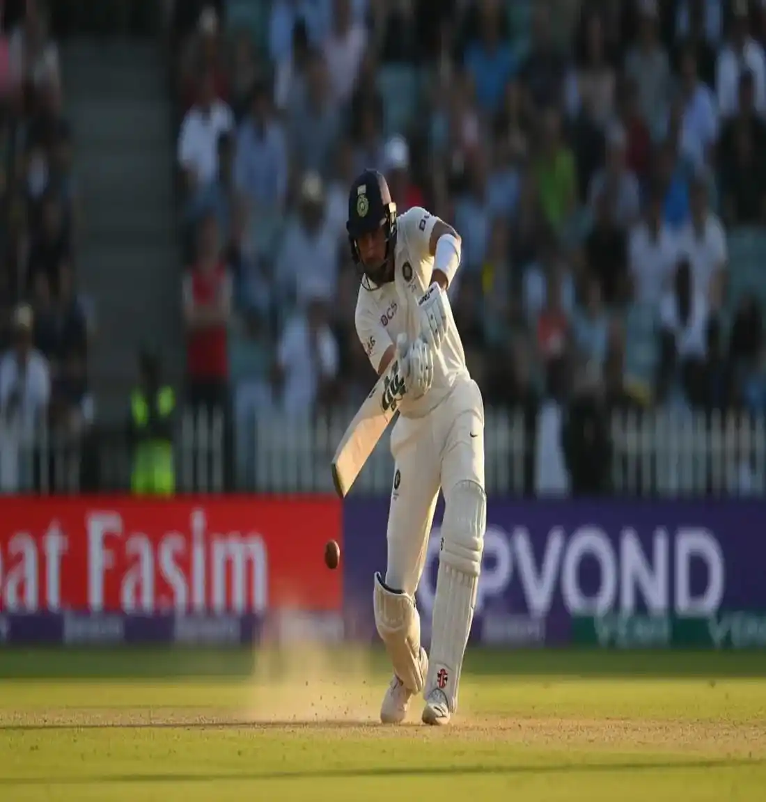 Cricket batsman in white Test attire playing defensive shot showing elite technique and concentration