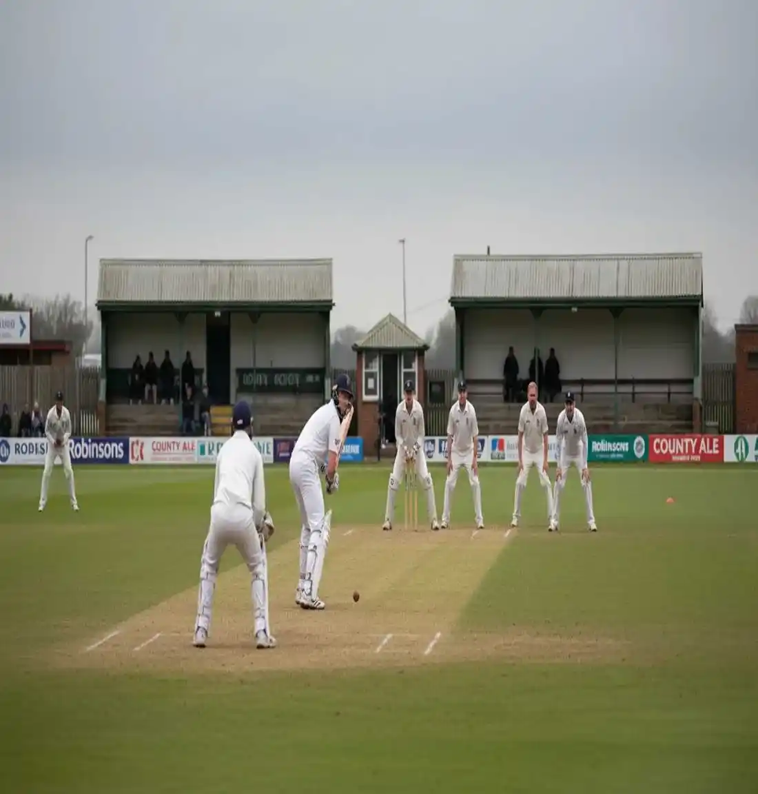 Four-day County Championship cricket match showing batsman and fielders under overcast English sky